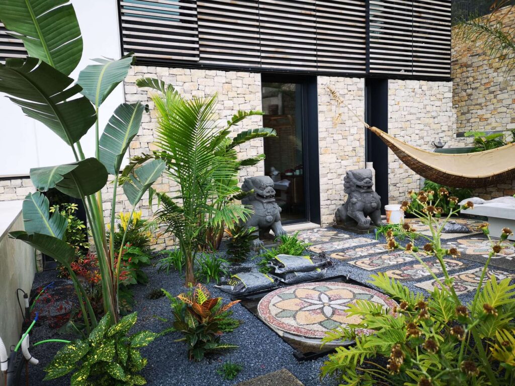 Jardín pequeño pero espectacular, con zona de estar, jardineras verticales, macetas agrupadas y luces cálidas que crean un gran impacto visual.