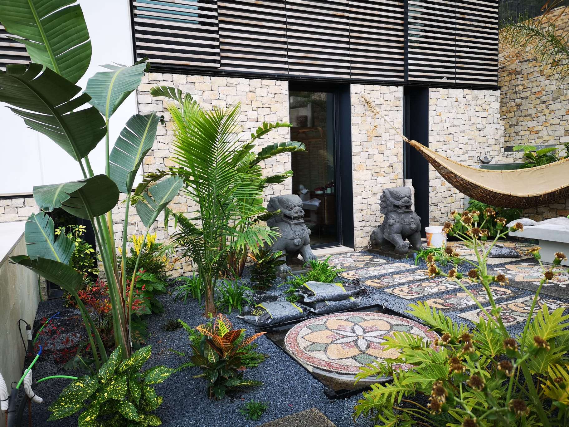 Jardín pequeño pero espectacular, con zona de estar, jardineras verticales, macetas agrupadas y luces cálidas que crean un gran impacto visual.