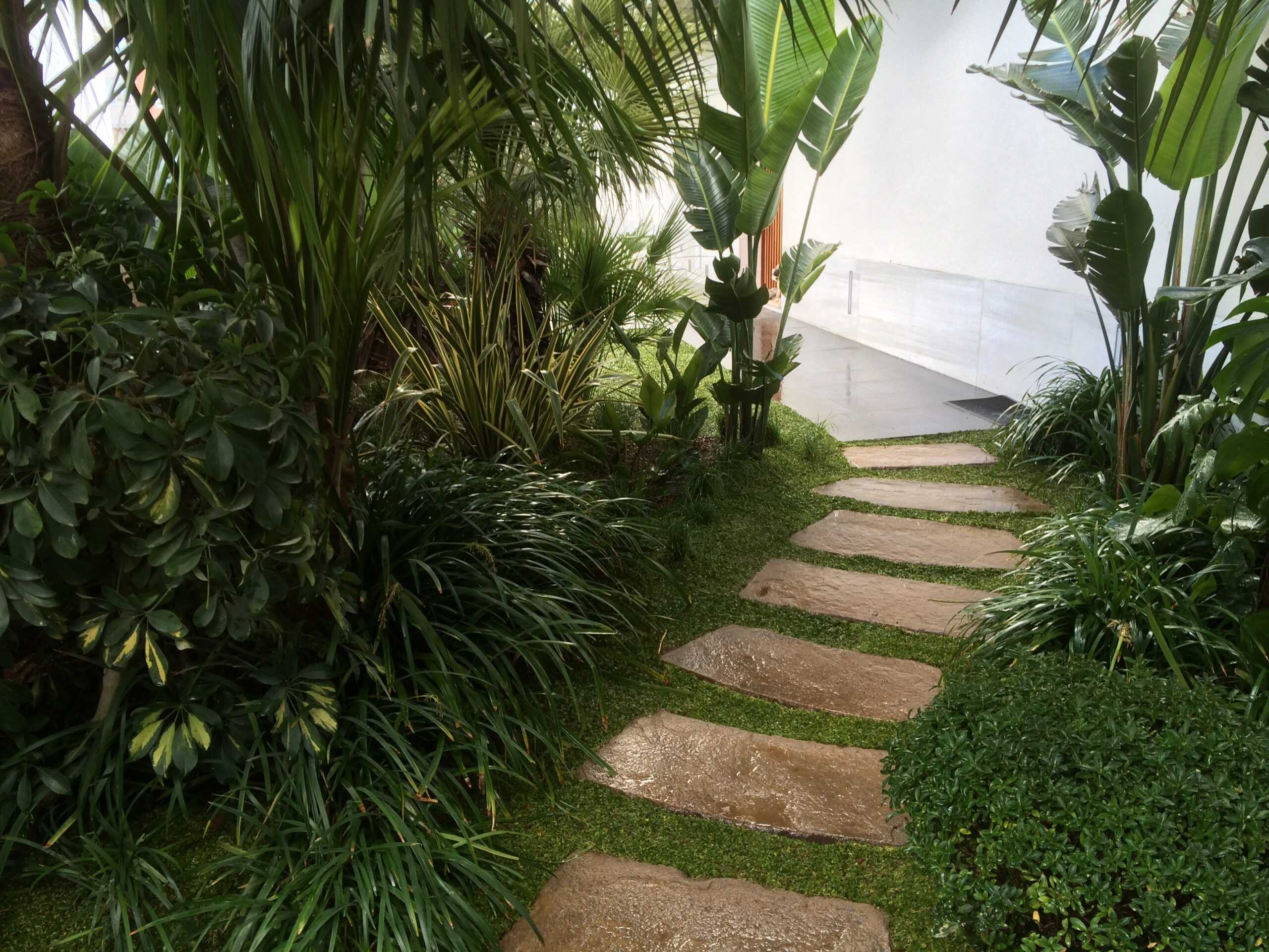 Persona marcando una checklist de tareas de mantenimiento de jardín sobre una tabla de madera, con herramientas y macetas a su alrededor.