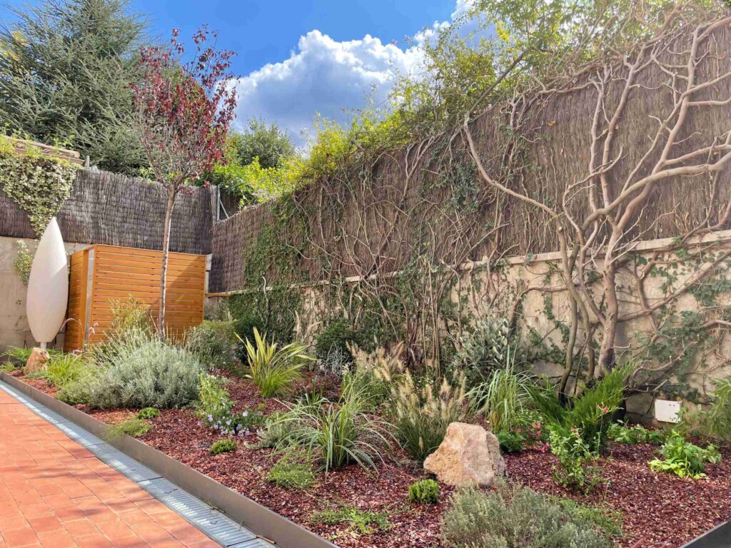 Jardín de bajo mantenimiento con grava, arbustos mediterráneos y riego por goteo, diseñado para requerir poco trabajo durante todo el año.