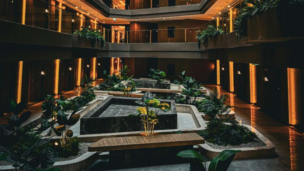 Vista de los jardines y la piscina de un hotel, con césped, palmeras y zonas de descanso bien mantenidas, vistos desde la perspectiva de un gerente.