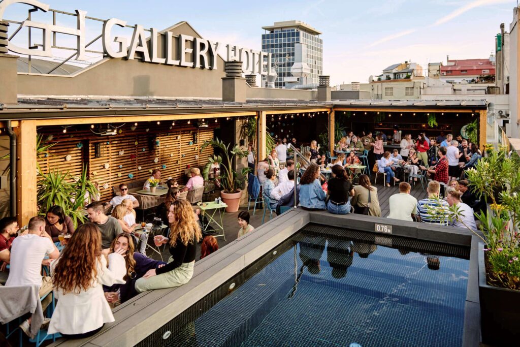 Terraza de restaurante con jardineras, plantas colgantes y jardines verticales que crean un ambiente acogedor y verde para los comensales